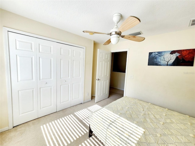 carpeted bedroom with ceiling fan, a textured ceiling, and a closet