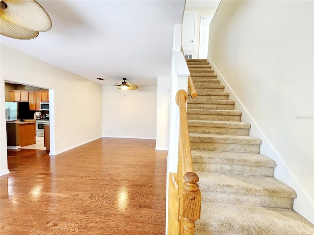 staircase with lofted ceiling, hardwood / wood-style floors, and ceiling fan