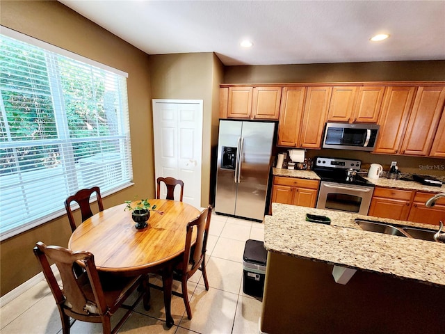 kitchen featuring light stone countertops, sink, light tile patterned flooring, and stainless steel appliances