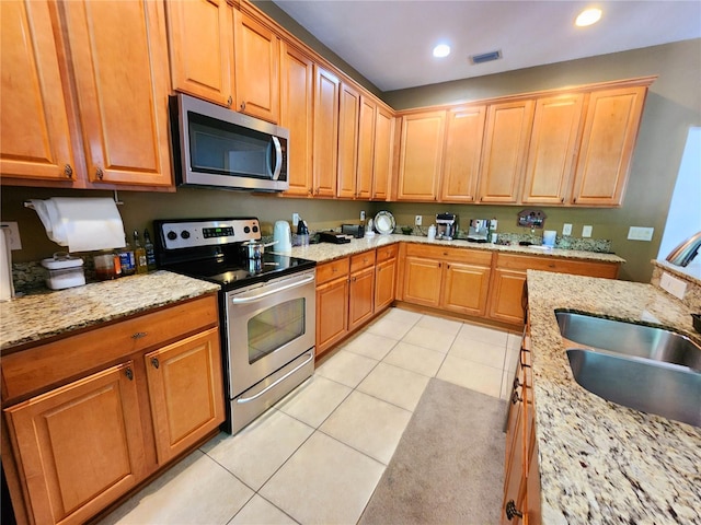 kitchen with stainless steel appliances, light stone countertops, sink, and light tile patterned floors