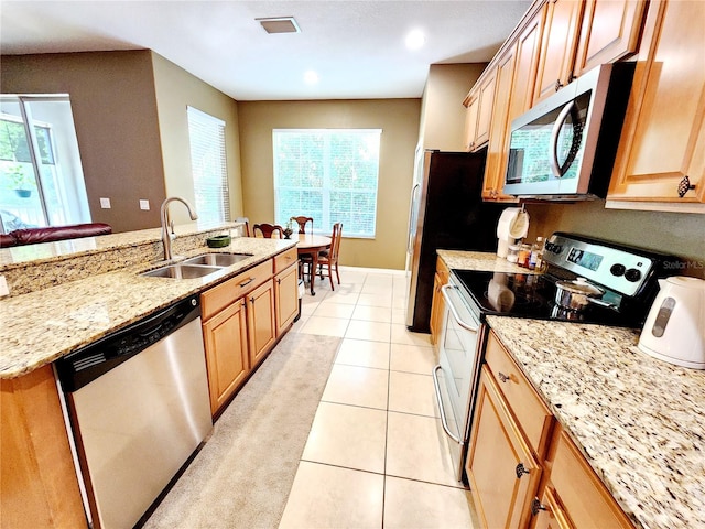 kitchen featuring appliances with stainless steel finishes, light stone countertops, sink, and light tile patterned floors