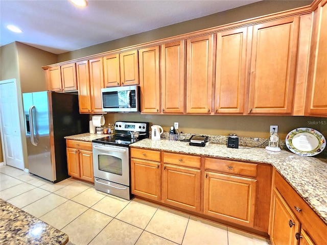 kitchen with light stone countertops, light tile patterned floors, and appliances with stainless steel finishes