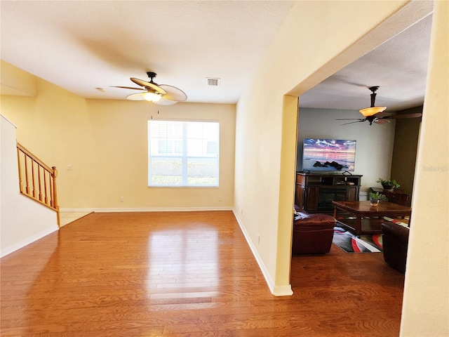 living room with hardwood / wood-style flooring, ceiling fan, and a fireplace