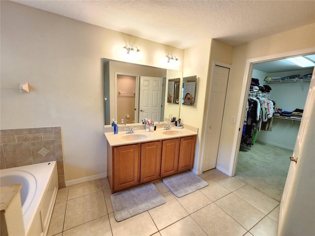 bathroom featuring a tub to relax in, tile patterned floors, vanity, and a textured ceiling