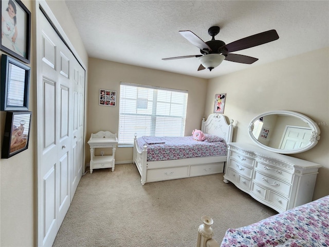 carpeted bedroom with ceiling fan, a textured ceiling, and a closet