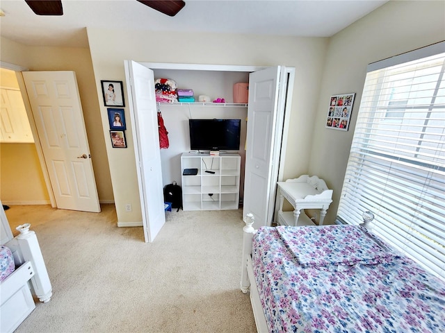 bedroom featuring light colored carpet, a closet, and ceiling fan