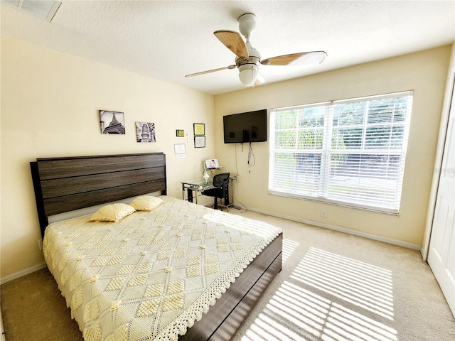 bedroom with a textured ceiling, light colored carpet, and ceiling fan