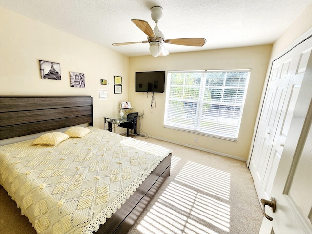 carpeted bedroom with ceiling fan, a closet, and a textured ceiling