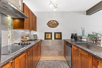 bar with sink, black electric cooktop, wall chimney exhaust hood, and stainless steel dishwasher