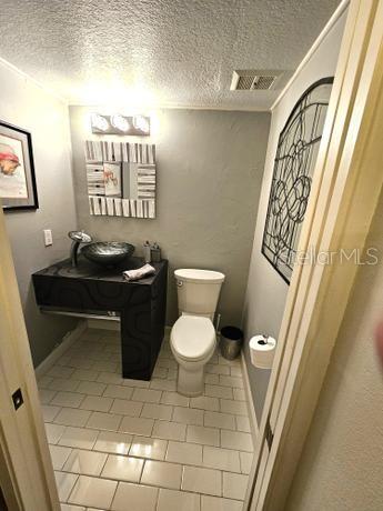 bathroom featuring tile floors, a textured ceiling, and toilet