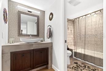 full bathroom featuring shower / bathtub combination with curtain, large vanity, and toilet