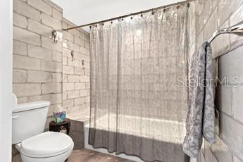 bathroom with toilet and tile walls