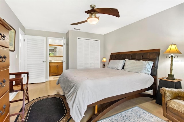 bedroom featuring a closet, ensuite bathroom, light wood-type flooring, and ceiling fan