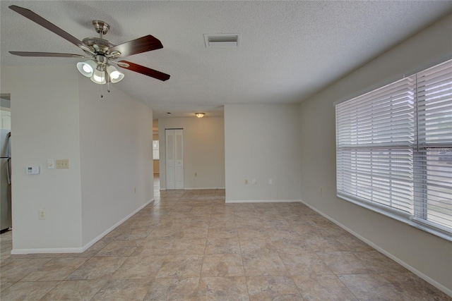 spare room with a textured ceiling, ceiling fan, and light tile floors