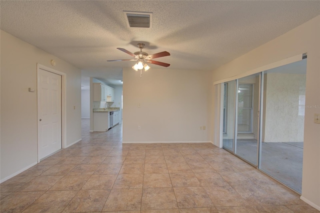 tiled spare room with ceiling fan and a textured ceiling