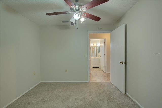 spare room featuring ceiling fan, a textured ceiling, and light colored carpet