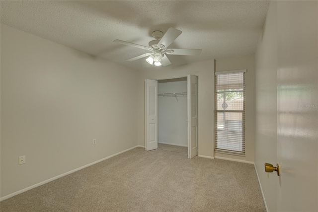 unfurnished bedroom featuring ceiling fan, a closet, a textured ceiling, and light colored carpet