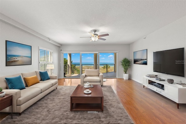 living room featuring hardwood / wood-style floors, ceiling fan, and a textured ceiling