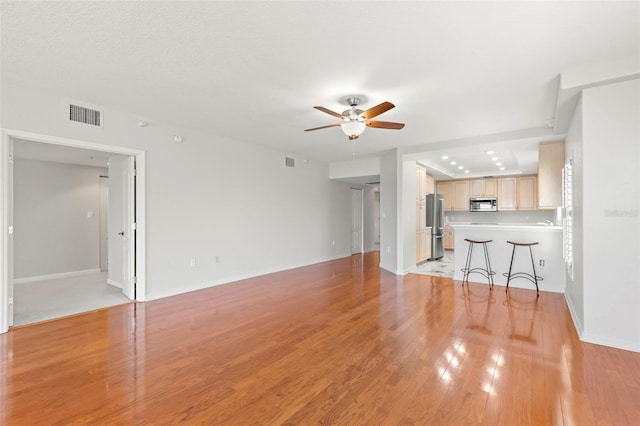 unfurnished living room with ceiling fan and light wood-type flooring