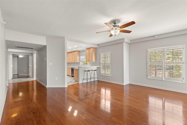 unfurnished living room with a textured ceiling, ceiling fan, and light tile floors