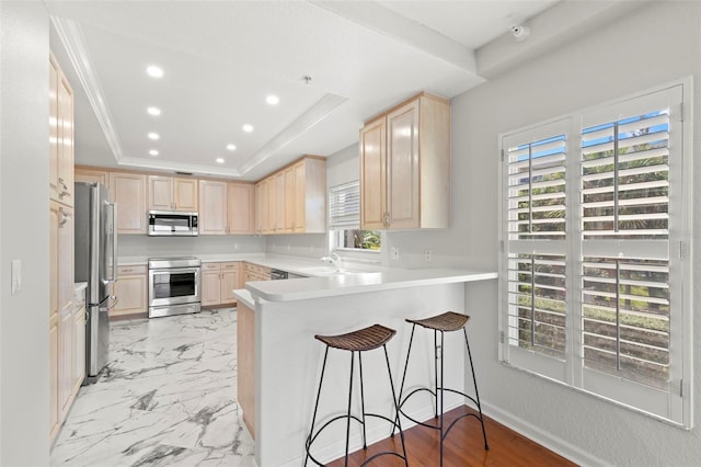 kitchen with stainless steel appliances, kitchen peninsula, light tile flooring, a raised ceiling, and light brown cabinets