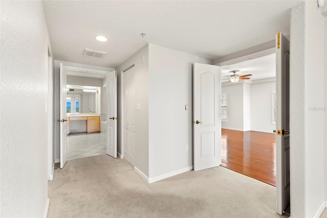 hall with light hardwood / wood-style floors and a textured ceiling