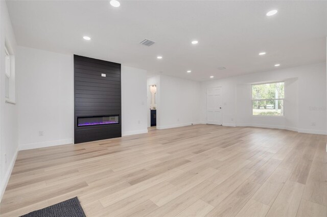 unfurnished living room with a large fireplace and light hardwood / wood-style floors