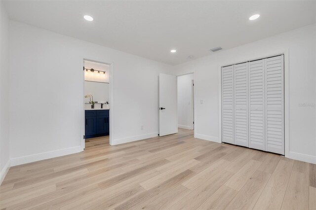 unfurnished bedroom with connected bathroom, light hardwood / wood-style floors, and a closet