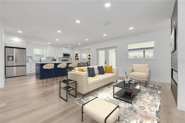 living room featuring sink, light hardwood / wood-style floors, and french doors