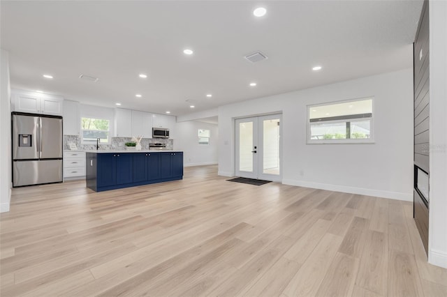 kitchen featuring appliances with stainless steel finishes, tasteful backsplash, white cabinets, light hardwood / wood-style floors, and french doors