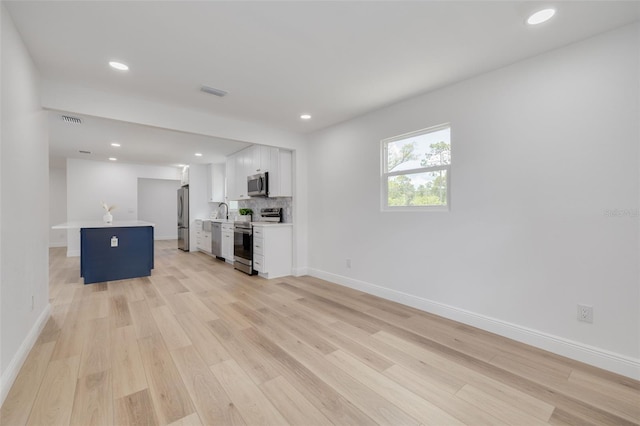 unfurnished living room featuring sink and light hardwood / wood-style floors