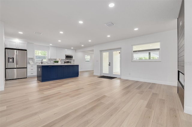 7414 Van Dyke Rd, Odessa, FL 33556 - kitchen featuring appliances with stainless steel finishes, french doors, a kitchen island, a sink, and light wood-style flooring