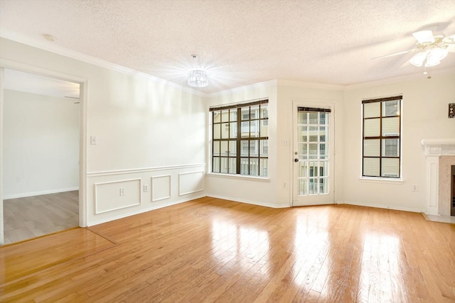 empty room with a high end fireplace, ceiling fan, light wood-type flooring, and ornamental molding