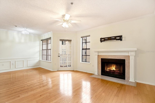 unfurnished living room featuring ceiling fan, a textured ceiling, a high end fireplace, and light wood-type flooring