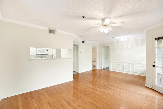 spare room featuring a textured ceiling, ornamental molding, ceiling fan, and light wood-type flooring