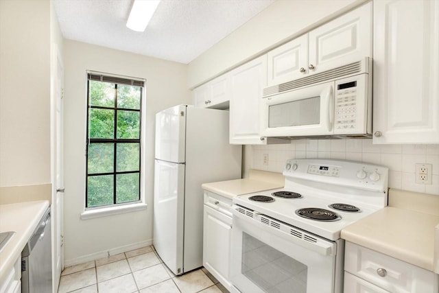 kitchen with white cabinetry, white appliances, a healthy amount of sunlight, and light tile floors