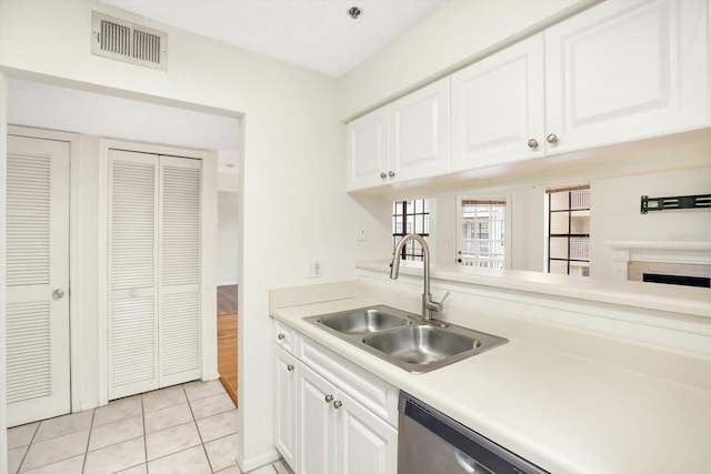 kitchen with sink, white cabinets, dishwasher, and light tile floors