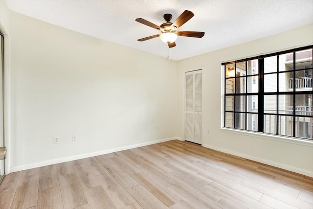 spare room with plenty of natural light, ceiling fan, and light wood-type flooring