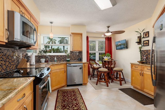 kitchen featuring stainless steel appliances, pendant lighting, tasteful backsplash, ceiling fan, and light tile floors