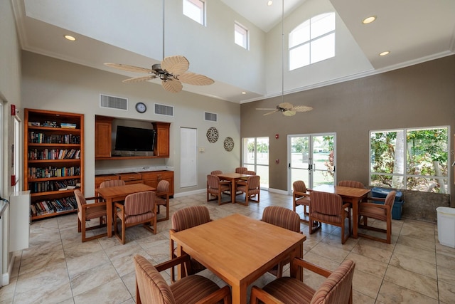 dining room with a towering ceiling, ceiling fan, and light tile floors