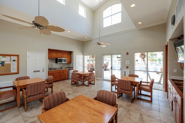 dining area featuring a high ceiling, sink, ceiling fan, and light tile floors