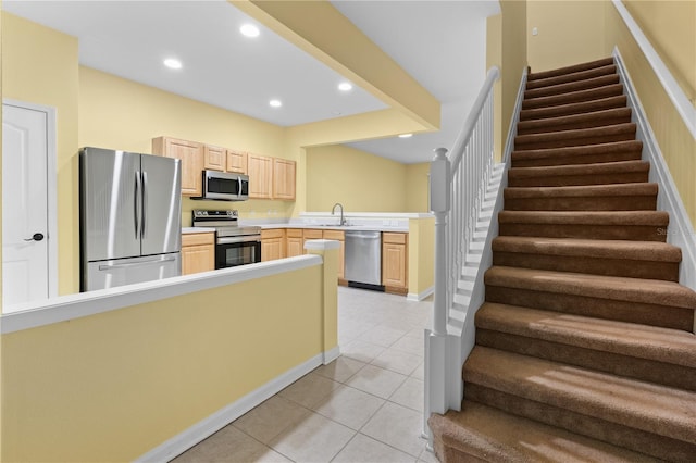 kitchen featuring appliances with stainless steel finishes, kitchen peninsula, sink, light tile flooring, and light brown cabinets