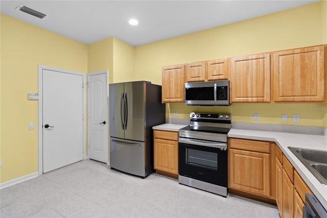 kitchen with light brown cabinets, stainless steel appliances, sink, and light tile floors