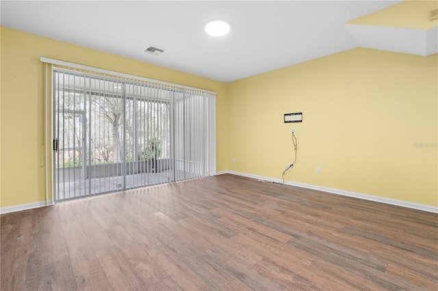 empty room featuring hardwood / wood-style flooring and lofted ceiling