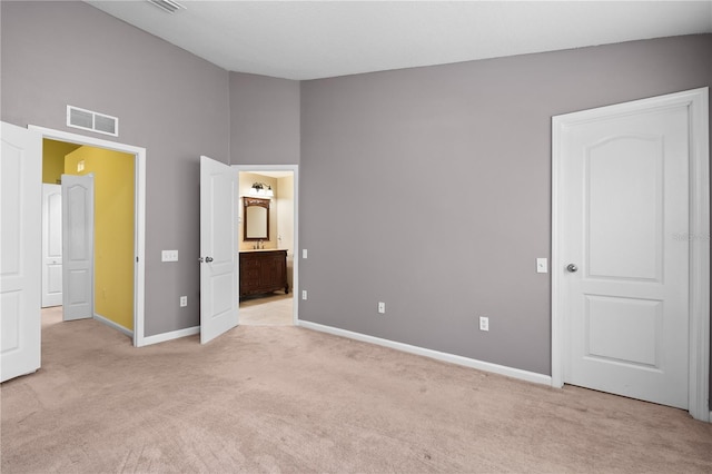 unfurnished bedroom with vaulted ceiling, light carpet, and ensuite bath