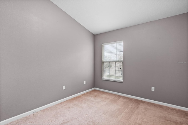 spare room featuring carpet and vaulted ceiling