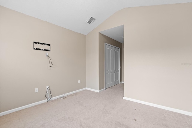 carpeted empty room featuring vaulted ceiling