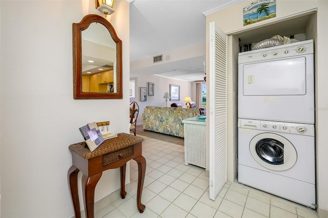 laundry room with light tile patterned floors and stacked washing maching and dryer