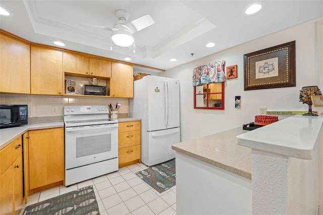 kitchen featuring kitchen peninsula, white appliances, ornamental molding, and a tray ceiling