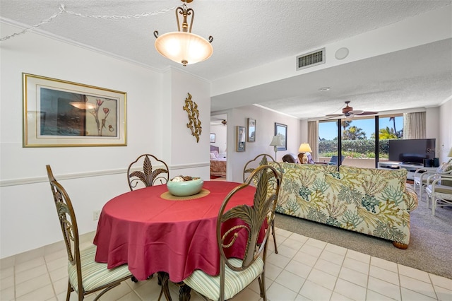 dining space with ceiling fan, light tile patterned flooring, ornamental molding, and a textured ceiling